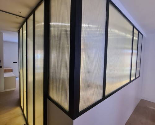 Cerramiento vestidor de perfilería ligera aluminio negro mate y vidrio acanalado.
