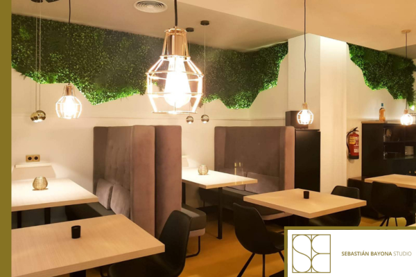 Interiorismo de restaurante en Barcelona con luz cálida, bancadas tapizadas y vegetación decorativa