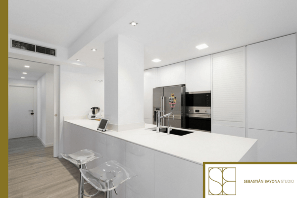 Modern white kitchen after renovation with large worktop, integrated appliances, and clean lines.